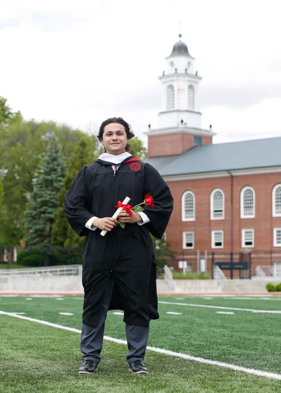 a man in a graduation gown holding a rose