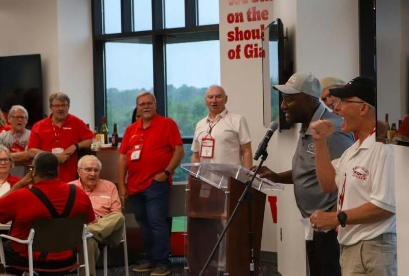 a man standing at a podium with a microphone in front of a group of people