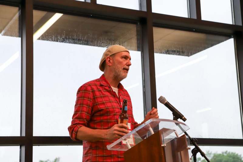 a man standing at a podium with a bottle of beer