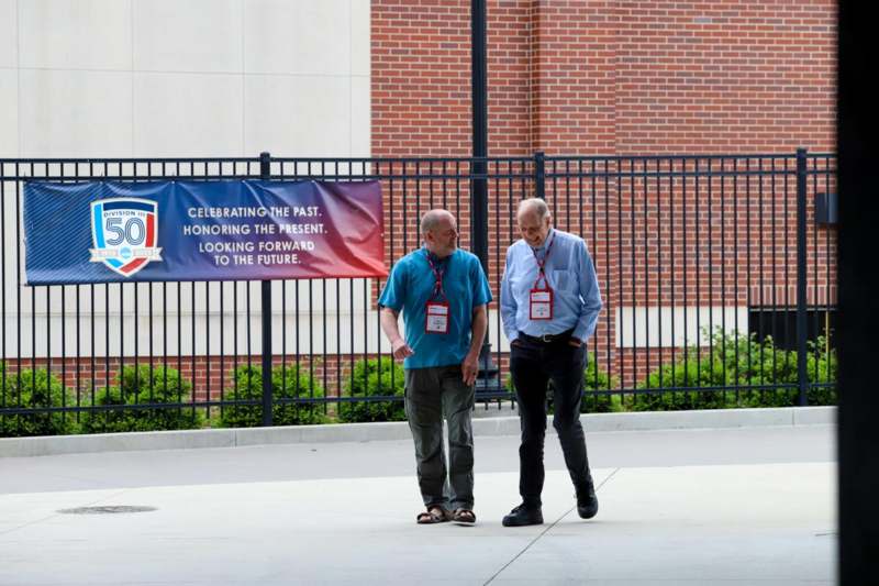 two men walking on a sidewalk