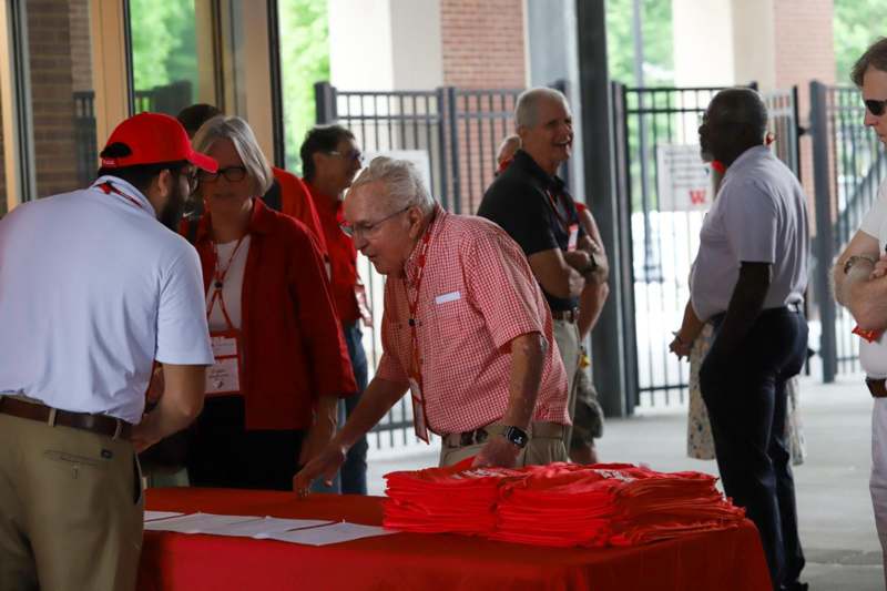a man standing at a table with folded red shirts