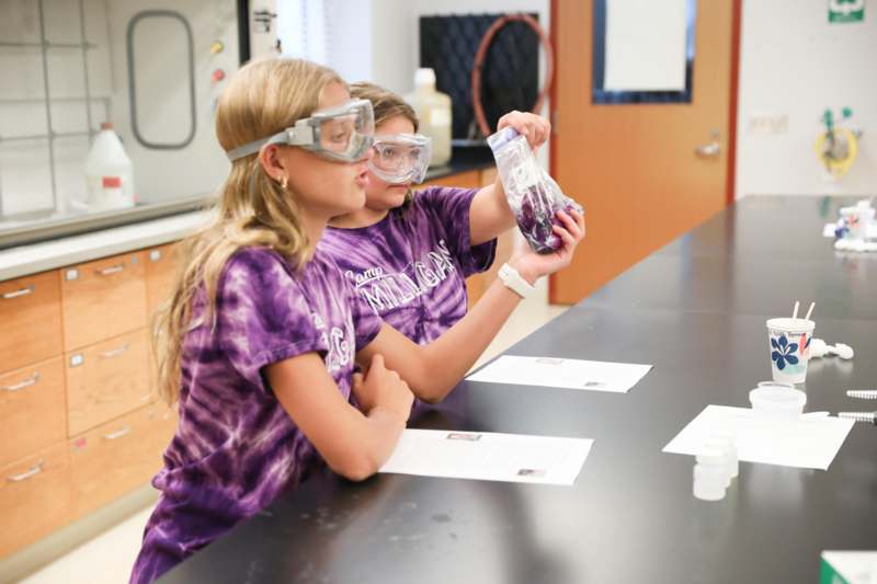 a girl wearing goggles and holding a bag of purple liquid