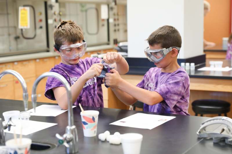 two boys wearing goggles and holding a purple object