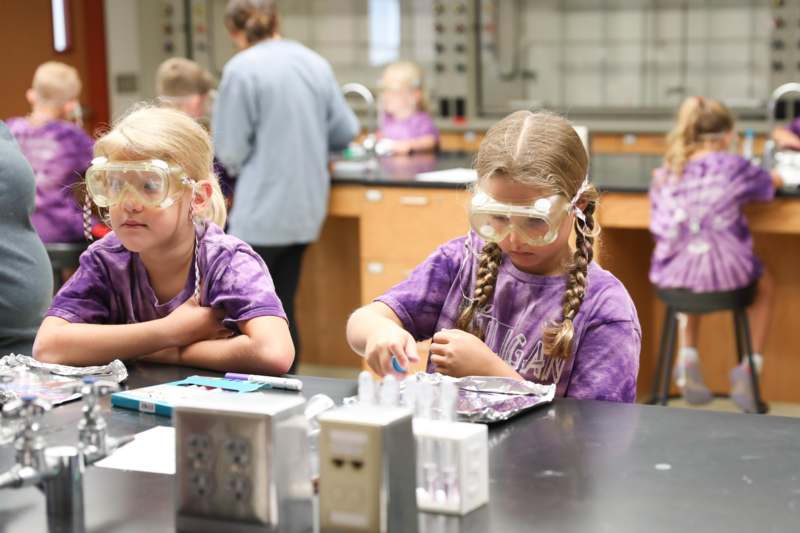a group of girls wearing safety goggles and looking at objects