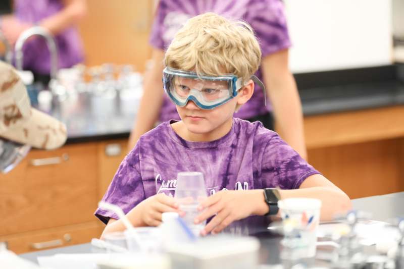 a boy wearing goggles and holding a glass