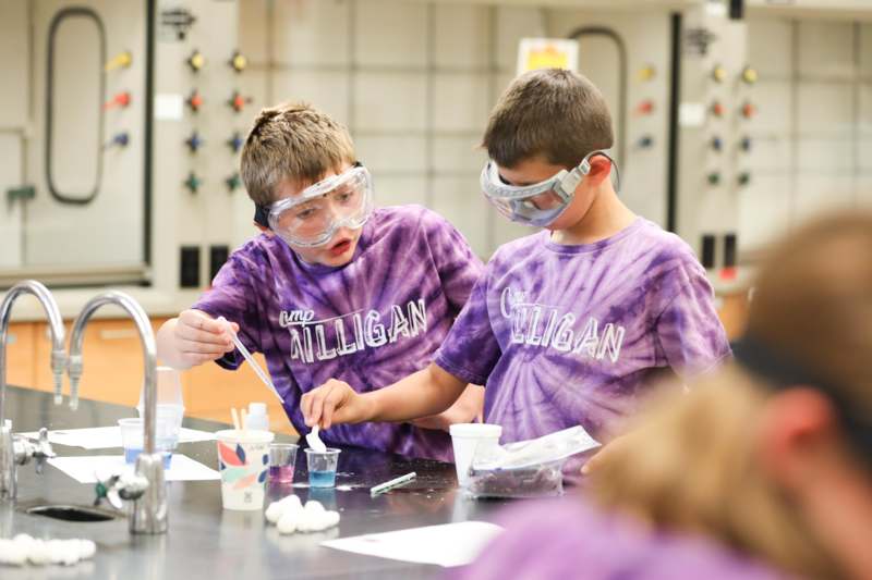 a pair of boys wearing safety goggles and holding a beaker