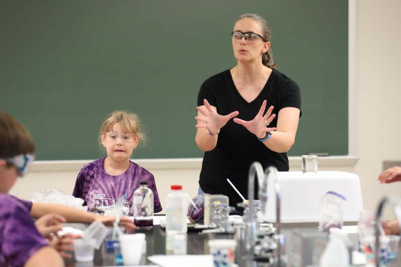 a woman standing in front of a table with a group of children