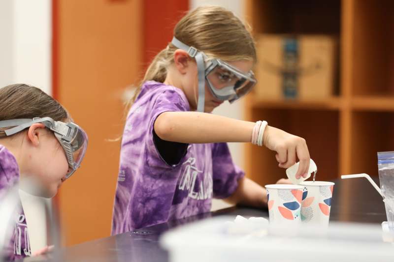 a group of kids wearing goggles and a mask pouring liquid into a cup