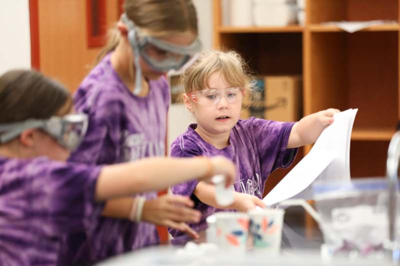 a group of children wearing safety goggles and holding a piece of paper