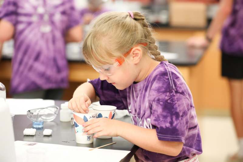 a girl wearing goggles and holding two cups