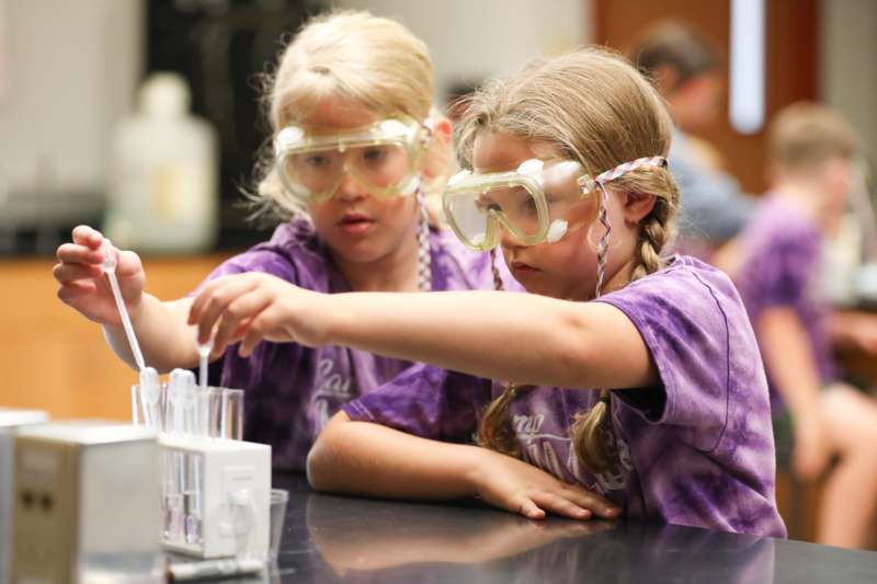 two girls wearing goggles and holding a pipette