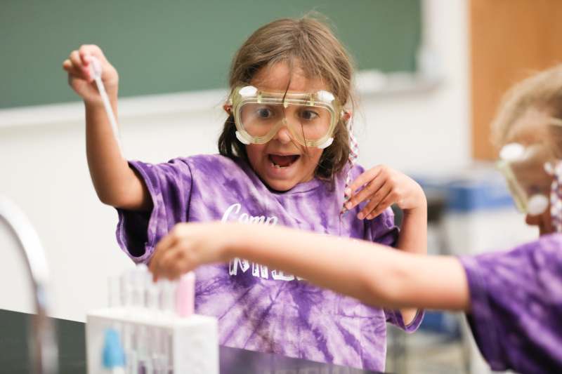 a girl wearing goggles and holding a test tube