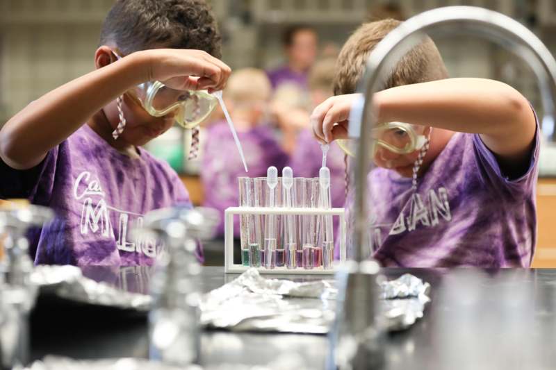 a group of kids in purple shirts doing experiments