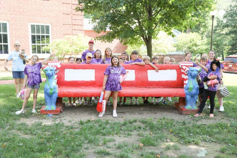 a group of kids posing for a photo in front of a bench