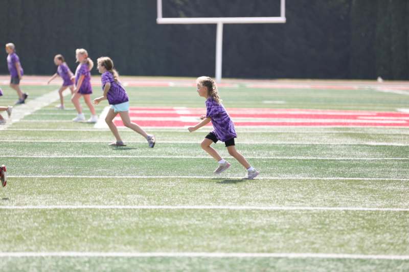 a group of girls running on a football field