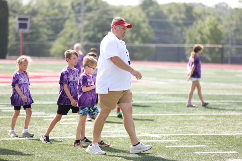 a man walking with kids on a field