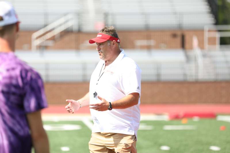 a man in a white shirt and tan shorts on a football field