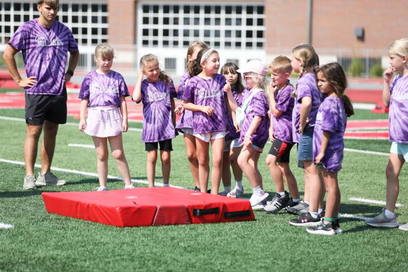 a group of kids standing around a red object on a field