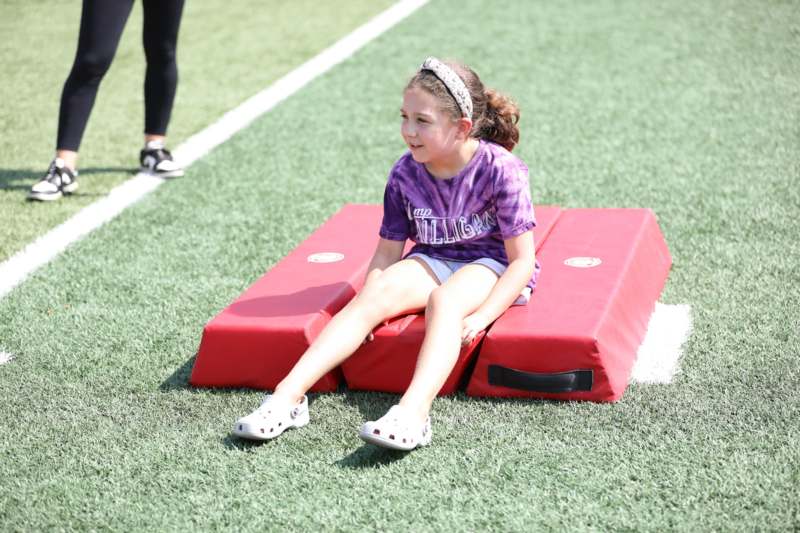 a girl sitting on a red pad on a field