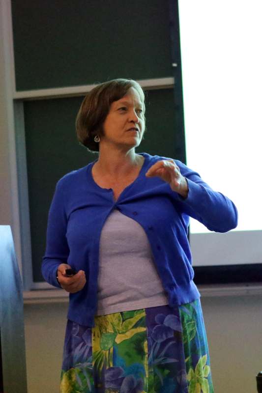 a woman in a blue cardigan holding a black object