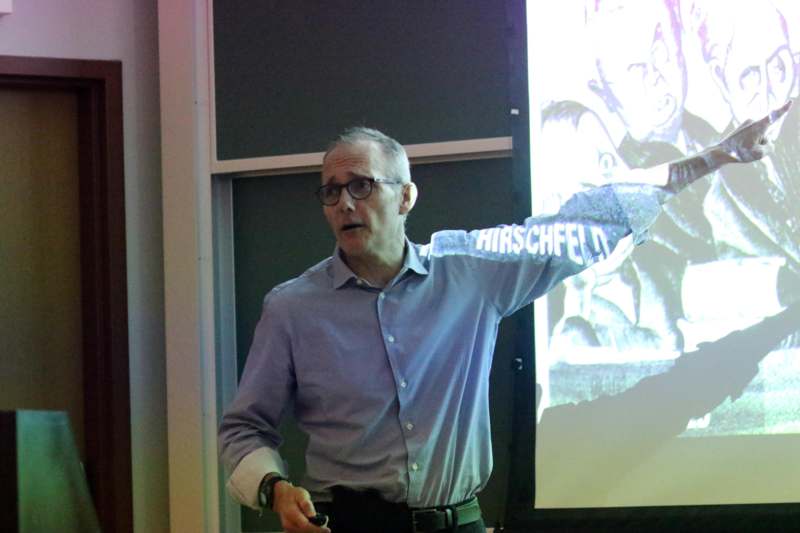 a man in glasses with his arm extended