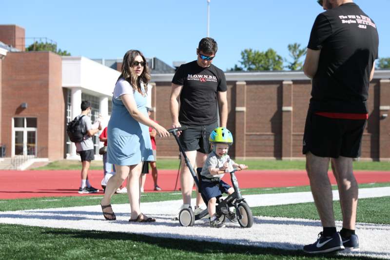 a man and woman walking with a child on a tricycle