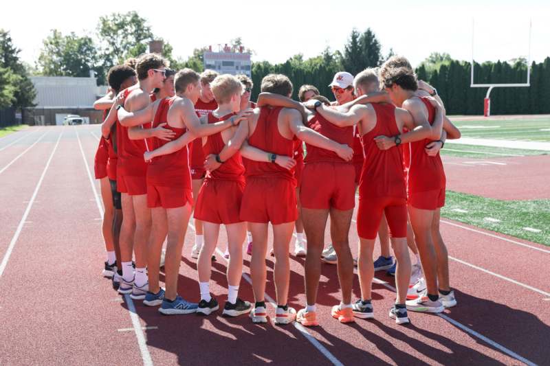 a group of people in red uniforms hugging on a track