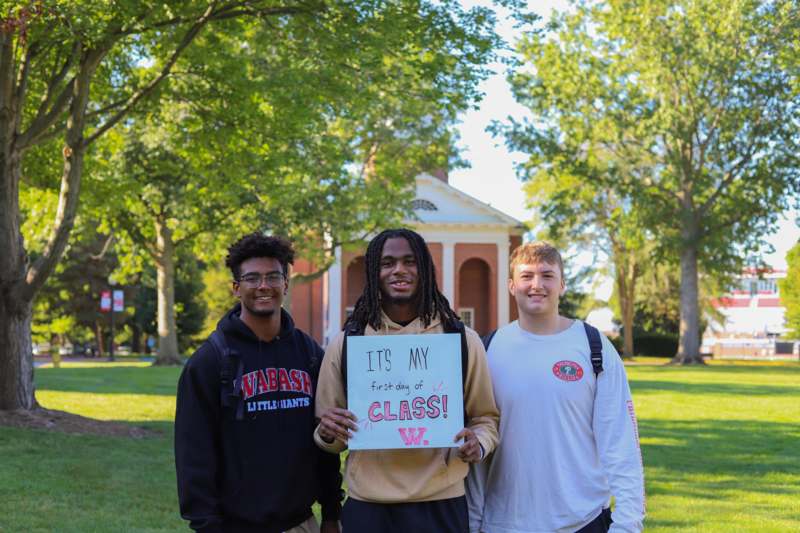 a group of men standing in front of a building holding a sign