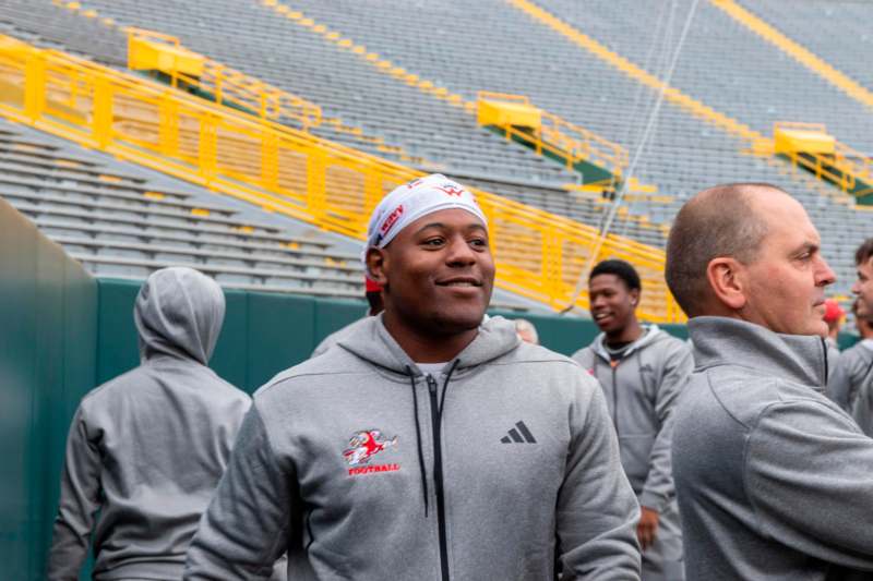 a man in grey hoodie and white headband standing in a stadium