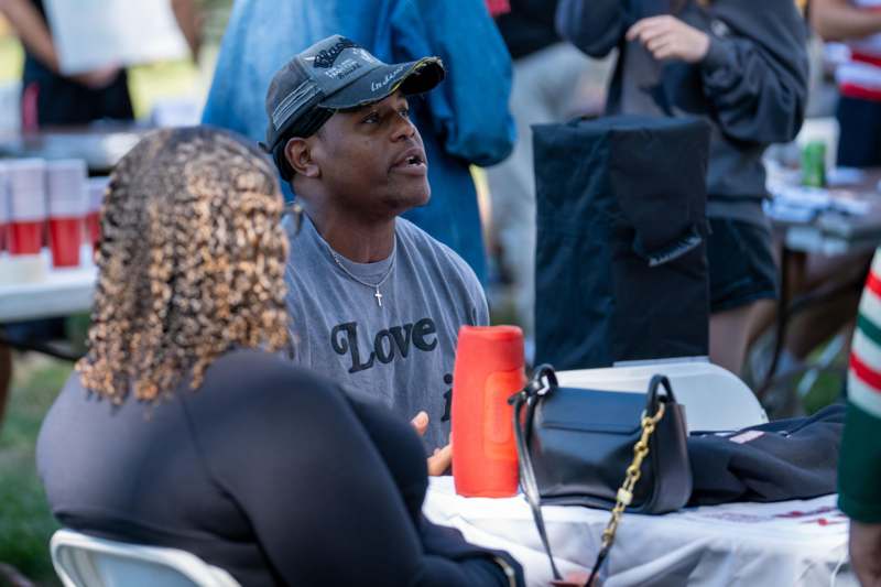 a man in a hat sitting at a table with a woman in the background