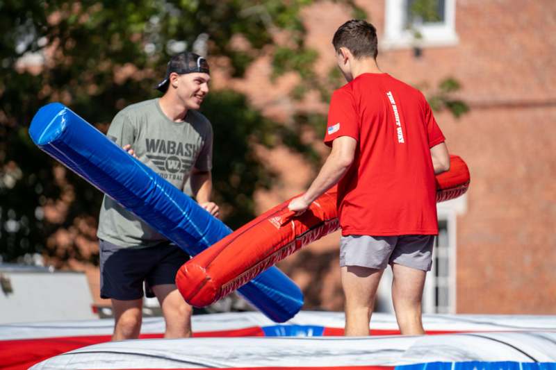 two men holding inflatables on a trampoline