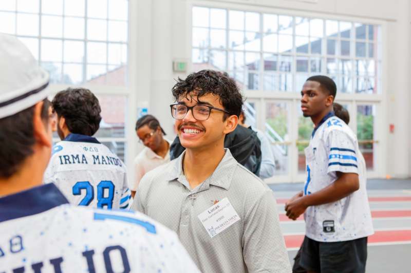 a man wearing glasses and a name tag smiling
