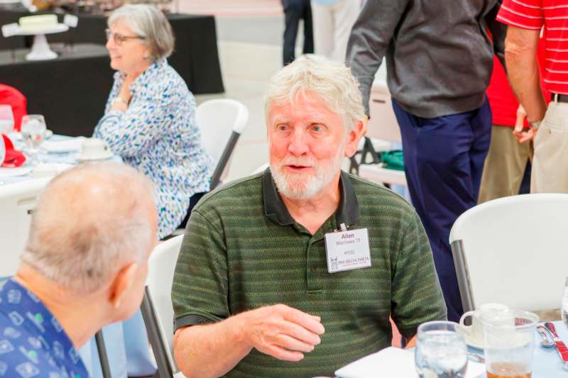a man sitting at a table with other people in the background