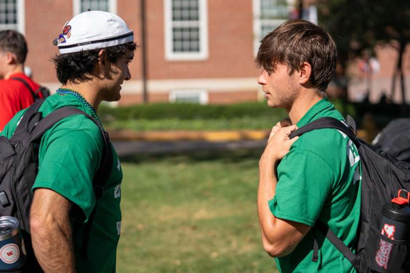 two men in green shirts talking to each other