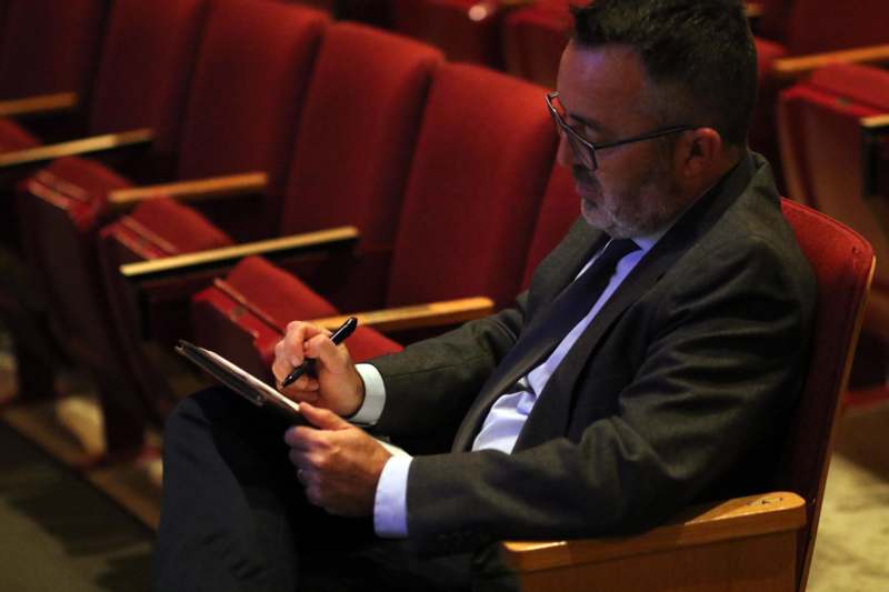 a man sitting in a chair writing on a clipboard