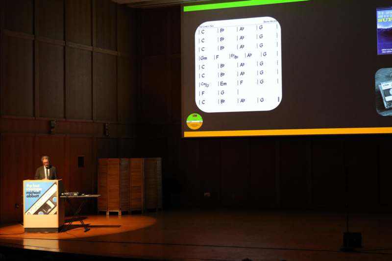 a person on stage with a projector screen
