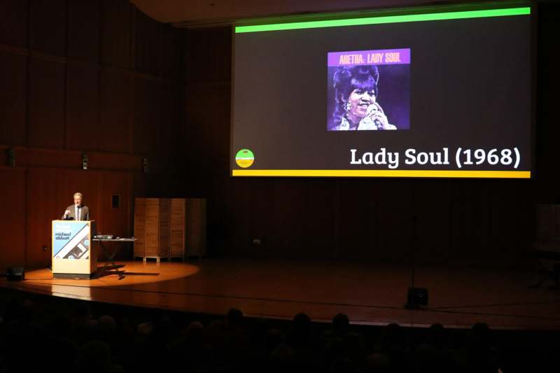 a woman on stage with a screen