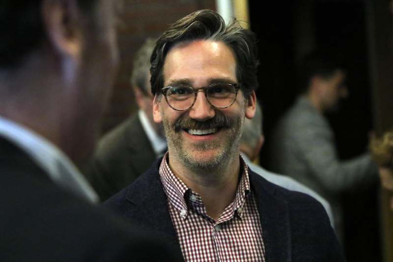 a man with glasses smiling