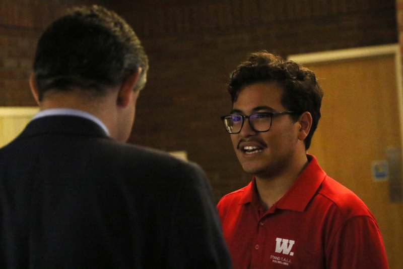 a man in a red shirt talking to another man