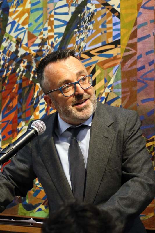 a man in a suit and tie speaking into a microphone