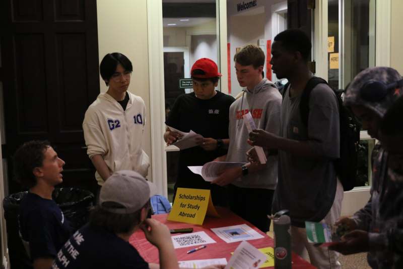 a group of people standing around a table with papers