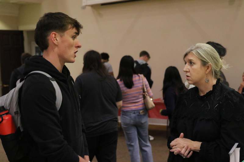 a man and woman talking in a room with other people
