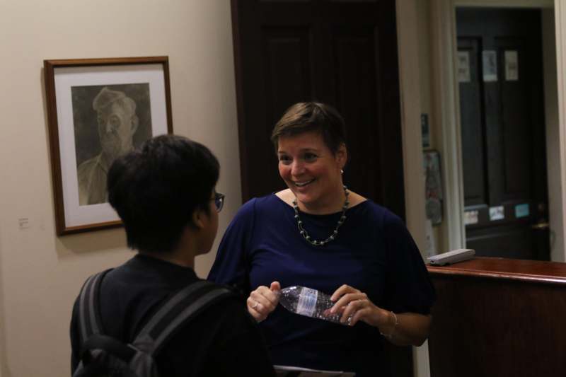 a woman holding a water bottle and talking to another woman