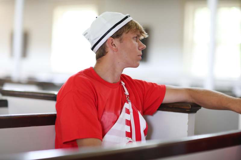a man in a red shirt and white hat leaning on a railing