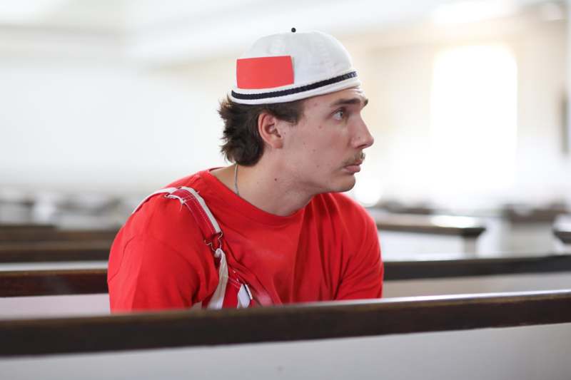 a man in a red shirt and white hat sitting in pews