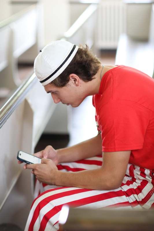 a man in a red shirt and striped pants looking at a cell phone