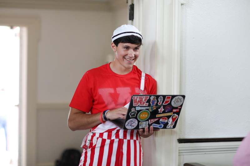 a man in a red and white striped shirt holding a laptop