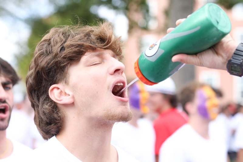 a man pouring a green bottle into his mouth