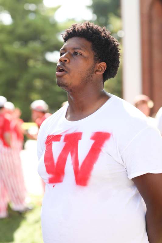 a man wearing a white shirt with a red letter on it