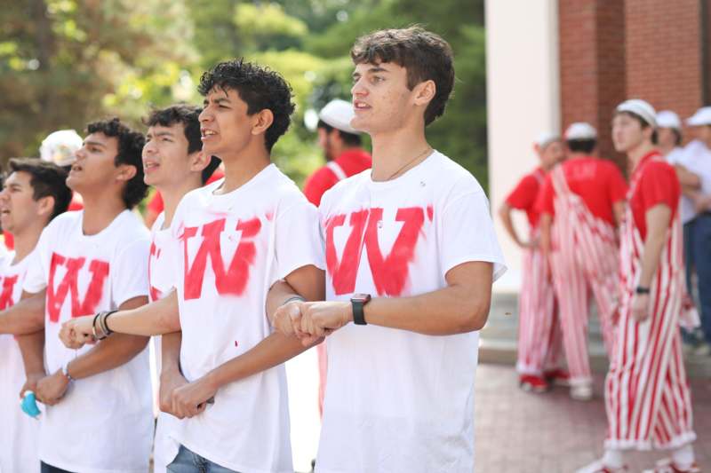 a group of young men in white shirts with red letters